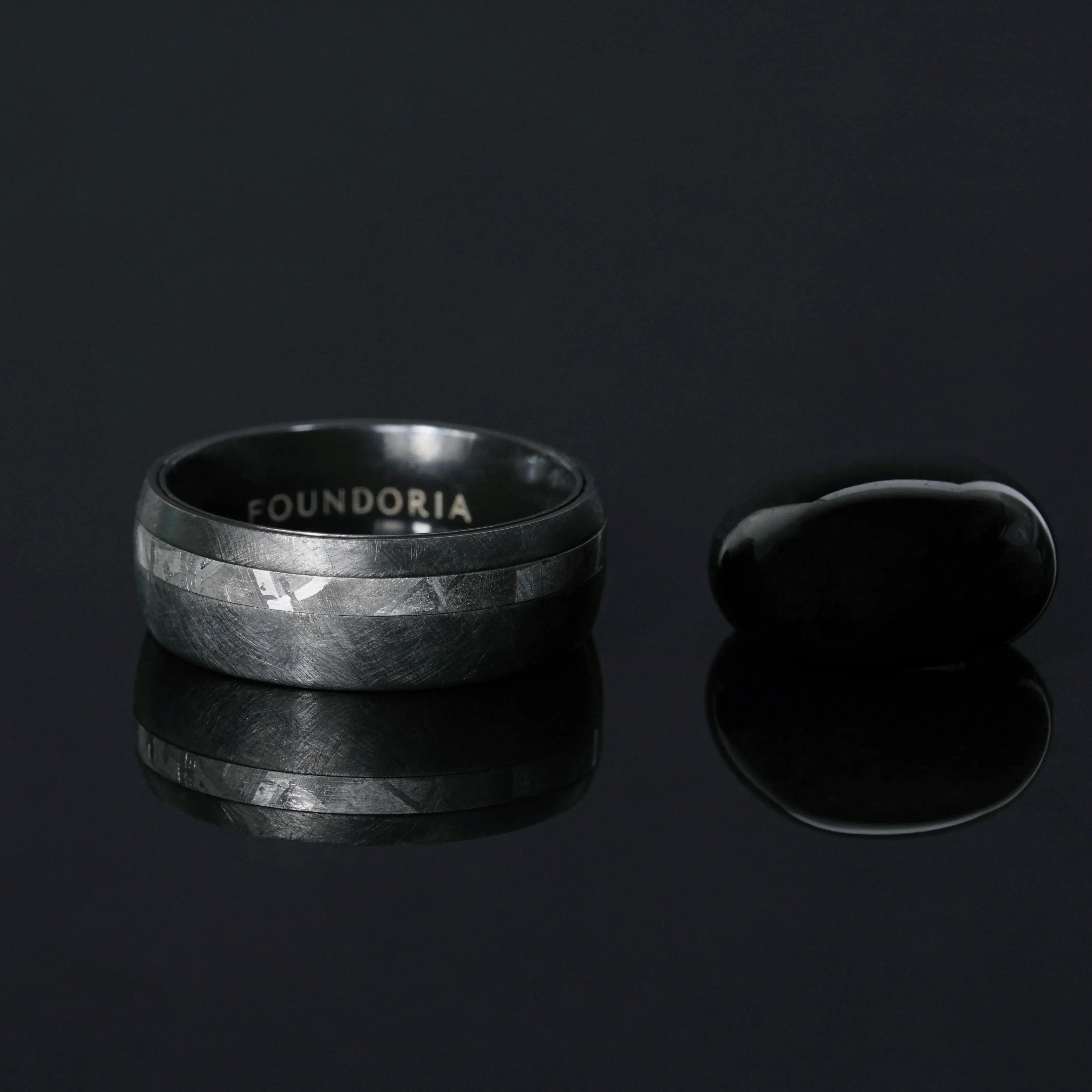Nyx black zirconium ring with an offset meteorite line, worn on the hand